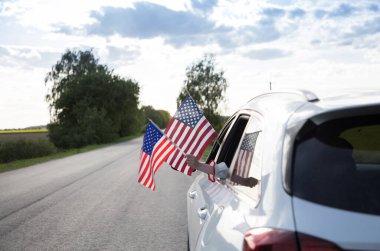 Arabanın camından sarkan iki Amerikan bayrağı. ABD Bağımsızlık Günü 4 Temmuz. Gurur, özgürlük, vatanseverlik, demokrasi. Ülkeyi dolaş. seçici odak