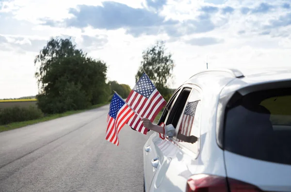 two American flags hanging out of the car window. USA Independence Day July 4th. Pride, freedom, patriotism, democracy. Travel around the country. selective focus