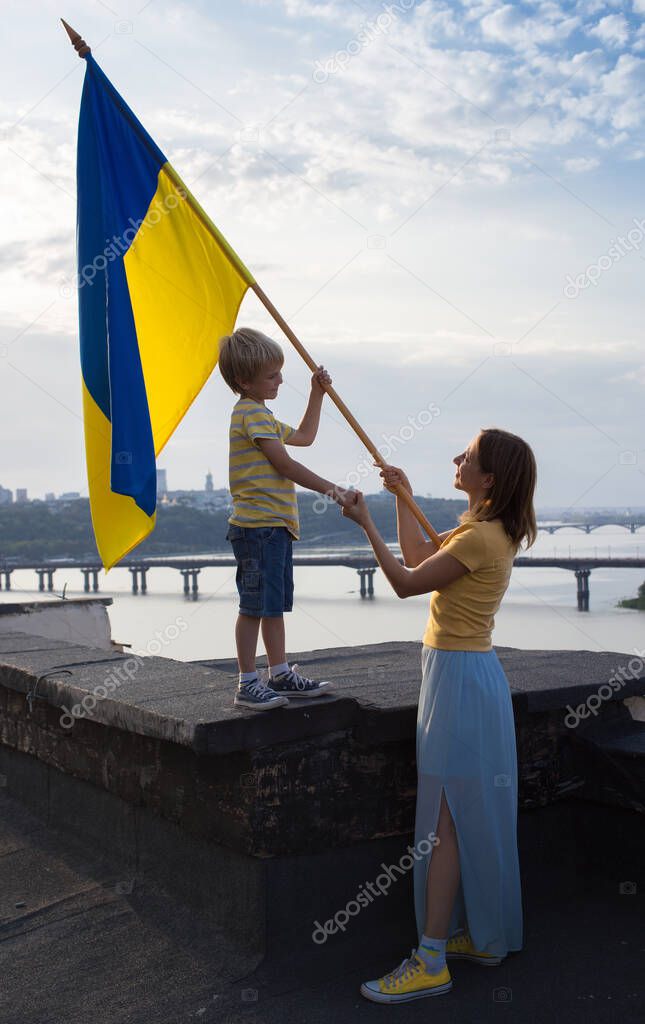 woman and child with Ukrainian flag stand on roof of house against backdrop of sky, Dnieper River in Kyiv. Patriotism, drawing attention to war in Ukraine. Support Ukraine, Hope and faith in victory