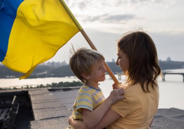 Kyiv 'deki bir evin yüksek çatısında Ukrayna bayrağıyla Dinyeper Nehri' nin üzerinde duran bir erkek ve bir kadının yüzleri. Aile, birlik, destek, birbirimiz hakkında, Ukrayna 'da özgürlük hayalleri. Savaşı durdurun.