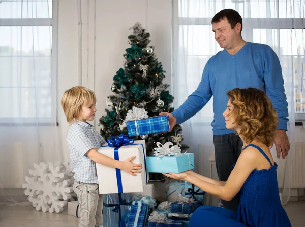 happy family, dad, adult daughter, son 5 years old on background of decorated Christmas tree, they exchange gifts before Christmas. Bright positive emotions on faces. atmosphere of celebration, love