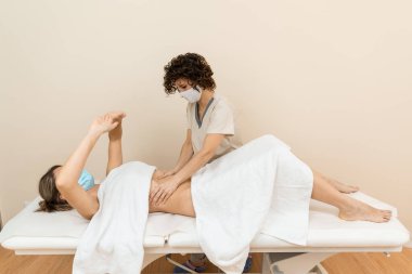 Karın masajı yapan bir terapist. Sağlık merkezindeki bir kadının karnına baskı yapıyor.