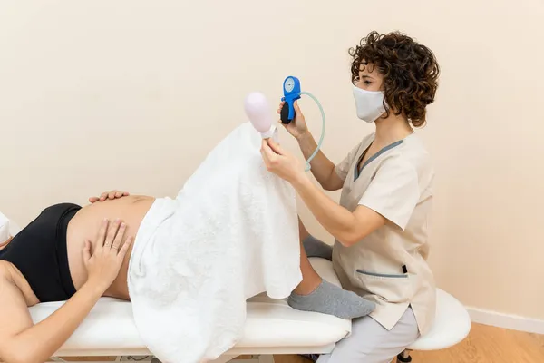 Gynecologist holding a pelvic floor muscle exercise device to prepare for the giving of birth of a woman lying — Stock Photo, Image