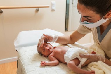 Yeni doğmuş bir bebekle tıp merkezinde çalışan kadın fizyoterapist..
