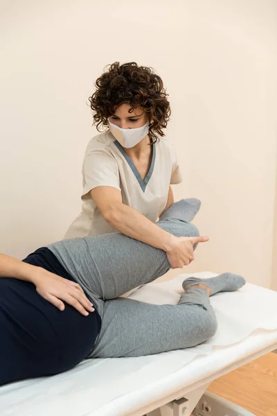 Fisioterapeuta masajeando piernas de mujeres embarazadas en el centro de salud —  Fotos de Stock