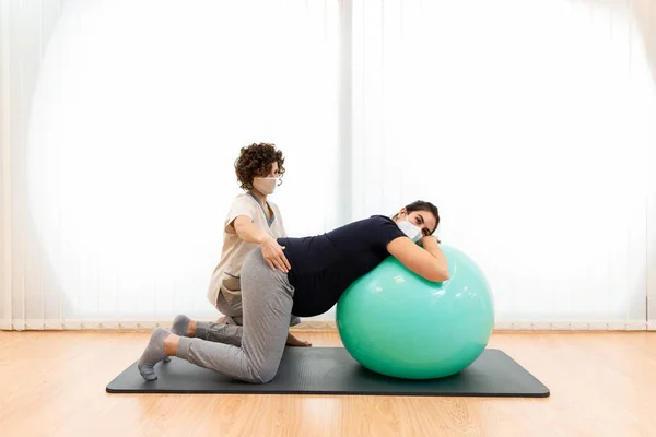 Hamile bir kadın fizyoterapistinin yardımıyla nefes egzersizleri yapıyor ve bir fitness topunun üzerinde dinleniyor. — Stok fotoğraf
