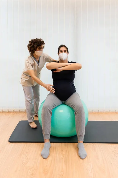 Fizioterapeuta segít egy terhes nőnek edzeni egy fitnesz labdán ülve. — Stock Fotó