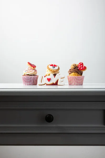 Magdalenas, magdalenas y galletas en forma de palabra amor y corazones, regalo de postre romántico — Foto de Stock
