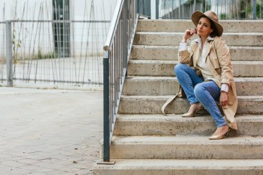 Sokakta merdivenlerde otururken düşünceli bir kadın bir şey düşünüyor..