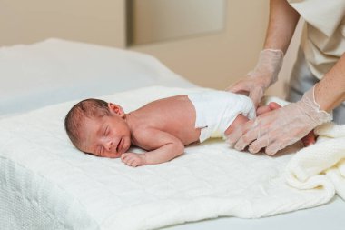 Professional physiotherapist doing an evaluation of the spine of a newborn baby.