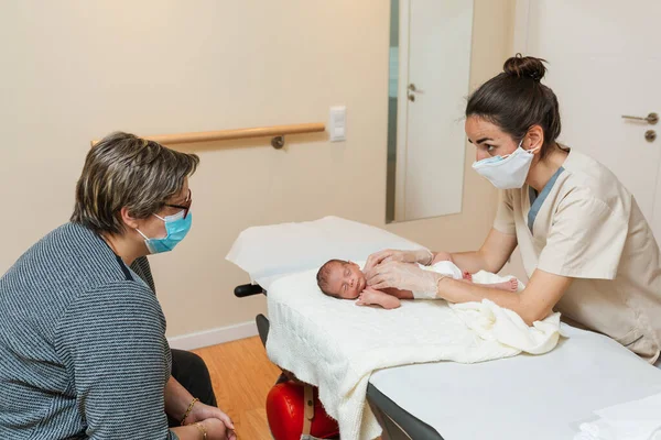 Female physiotherapist performing a clavicle and first rib assessment on a newborn baby. — стоковое фото