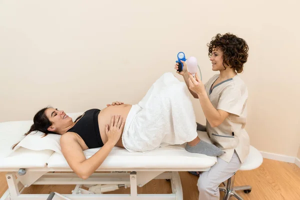 Ginecólogo sosteniendo un dispositivo de ejercicio muscular del suelo pélvico para prepararse para el parto de una mujer acostada — Foto de Stock