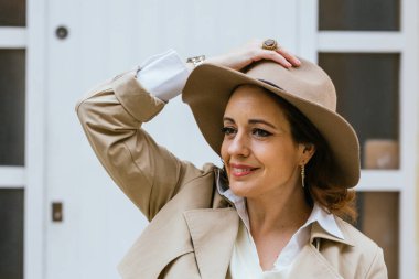 Sıcak elbiseli bir kadın sokakta dikilirken başka tarafa bakıyor ve gülümsüyor..