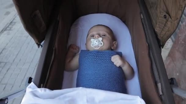 ベビーカーに乗っている間にペースメーカーを吸っている小さな赤ちゃん. — ストック動画