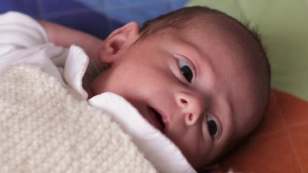 Vista da vicino di un neonato curioso di lato mentre sdraiato sulla schiena su un letto. — Video Stock
