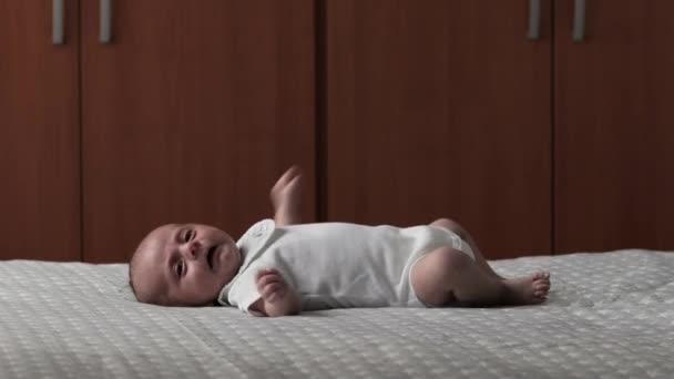 Bebé recién nacido moviéndose mientras está acostado boca arriba en una cama. — Vídeos de Stock