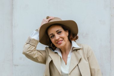 Sıcak elbiseli bir kadın sokakta dikilirken başka tarafa bakıyor ve gülümsüyor..
