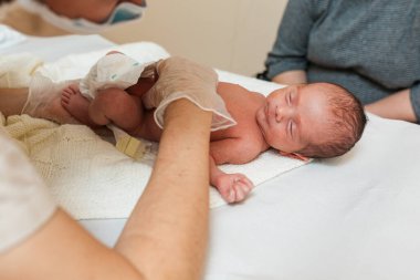 Fizyoterapist yeni doğmuş bir bebeği muayene ediyor..