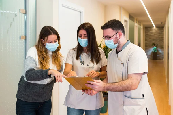 Doctora y su asistente médico ayudan a un paciente a llenar un formulario en un centro de atención médica. —  Fotos de Stock