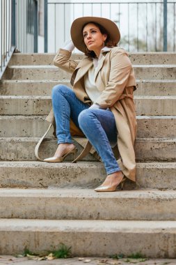 Sokakta merdivenlerde otururken düşünceli bir kadın bir şey düşünüyor..