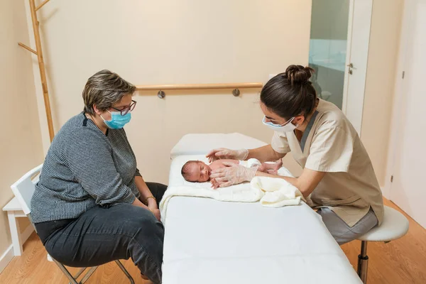 Női gyermekgyógyász, aki az újszülöttel dolgozik egy orvosi központban.. — Stock Fotó