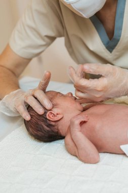 Fizyoterapist, bir tıp merkezinde yeni doğmuş bir bebeğin çene kemiği üzerinde değerlendirme yapıyor..