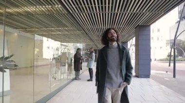 Finans bölgesinde ofis binasının dışında yürürken gülümseyen kendinden emin ve başarılı bir işadamı..