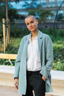 Profesyonel iş kadını şehir sokaklarında dikilirken kameraya bakıyor..