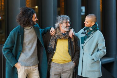 İş adamları sokakta yan yana dururken birbirlerine bakıp gülümsüyorlar..