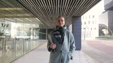 Kendine güvenen iş kadını ofis binasının dışında yürürken kameraya ciddi ciddi bakıyor..