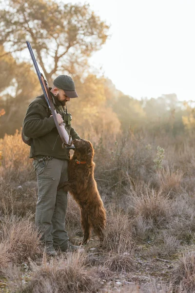 Jäger jagt mit Hund im Freien auf Feld. — Stockfoto