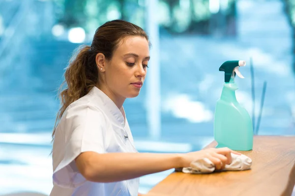 Kobieta wycierająca licznik środków dezynfekujących w nowoczesnej klinice — Zdjęcie stockowe