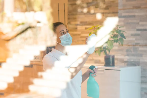 Donna in maschera medica finestra di lavaggio con detergente — Foto Stock