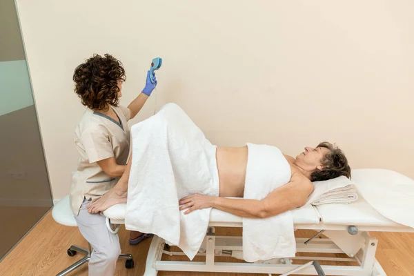 Physiotherapist holding radiofrequency machine for treatment of stimulation of the cells — Stock Photo, Image