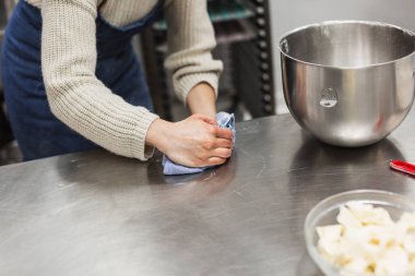Kadın fırında hamur işi tarifi yaptığı çalışma masasını temizliyor.