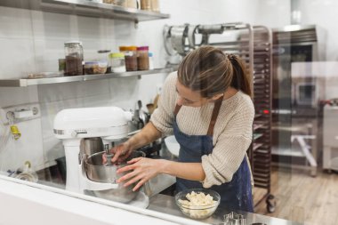 Büyük mutfakta karıştırmak için karıştırıcı hazırlayan kadın