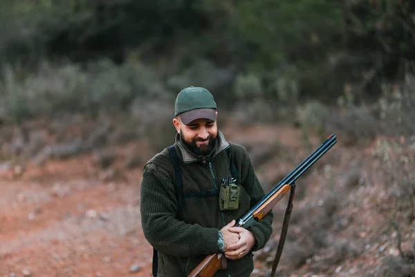 Portré vadászatról, ahogy a puskáját fogja és mosolyog, miközben lenéz. — Stock Fotó