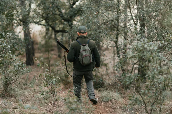 Männlicher Jäger mit Waffe bei Waldspaziergang auf der Suche nach Beute. — Stockfoto
