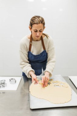 Kadın işçi hamurdan kurabiye kalıbı çıkarıyor.