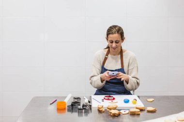 Pastanenin mutfağında çalışırken cep telefonunu kullanan kadın pasta şefi..