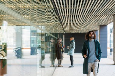 Modern iş adamları. Bazıları yürür, bazıları iş binalarının girişinde sohbet eder.