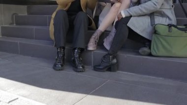 İş arkadaşları ofis binasının yakınındaki merdivenlerde otururken yeni projeler hakkında konuşuyor ve fikirlerini paylaşıyorlar..