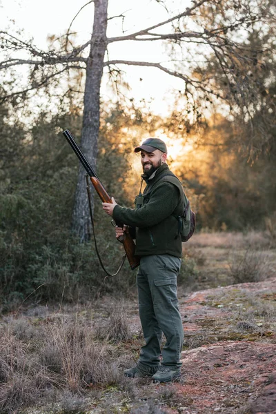 Férfi néz kamera és mosolyog, miközben tartja shotgun vadászat közben. — Stock Fotó