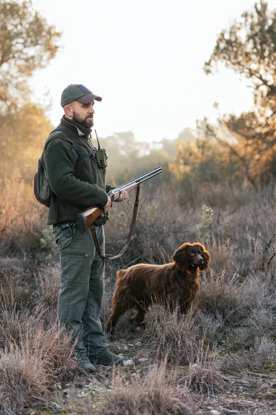 Junger Jäger steht mit Hund in der Natur und hält Schrotflinte — Stockfoto