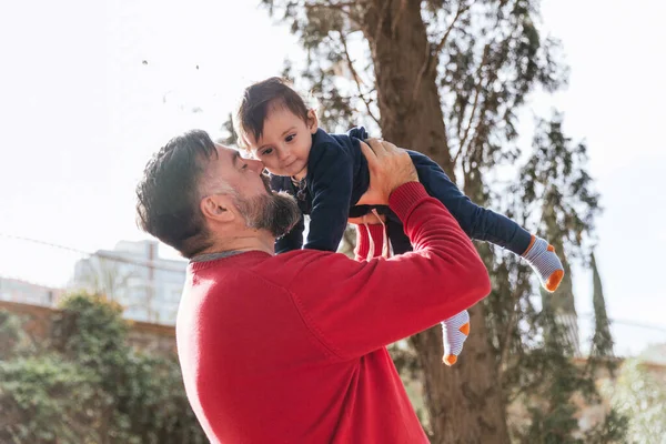 Dad holding his adorable little son in arms on sunny day at park — 스톡 사진