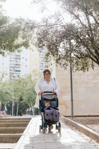 A mother walking her baby son in her stroller in the city — 스톡 사진