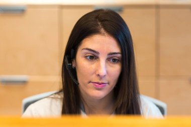 Sağlık ve Güzellik Merkezi resepsiyonunda çalışırken kulaklık takan bir resepsiyonist..