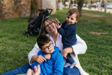 Özürlü çocuk, annesi ve küçük kardeşiyle parkta bir gün geçirmenin keyfini çıkarıyor..