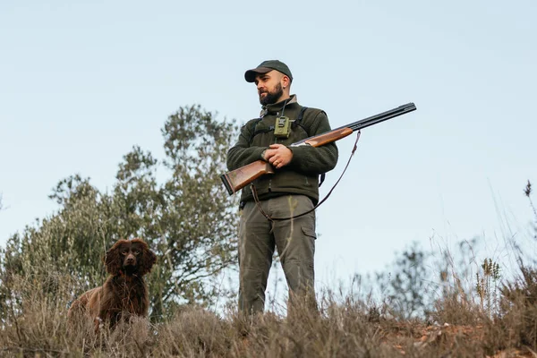 Jäger steht mit Hund im Gebirge und schaut weg — Stockfoto