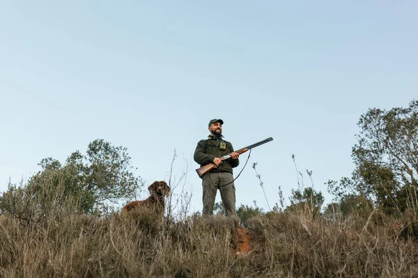Jäger hält sein Gewehr lächelnd in der Natur — Stockfoto